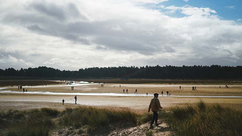 man walking along beach in Norfolk